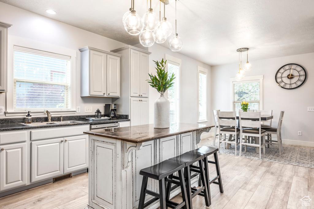 Kitchen with visible vents, a breakfast bar, a center island, a sink, and light wood-style flooring