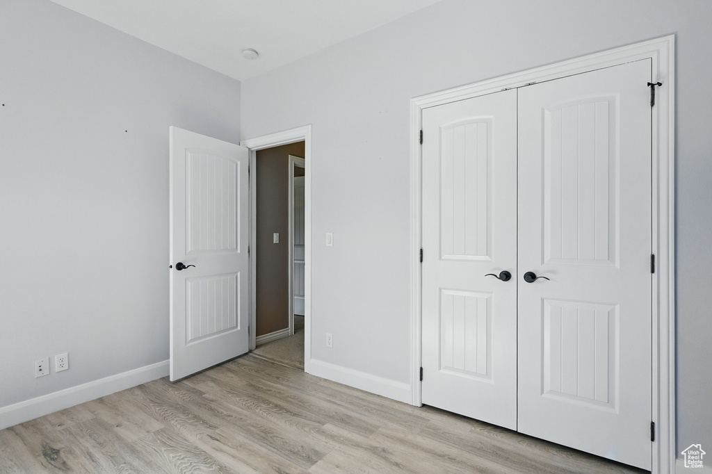 Unfurnished bedroom with light wood-style floors, baseboards, and a closet