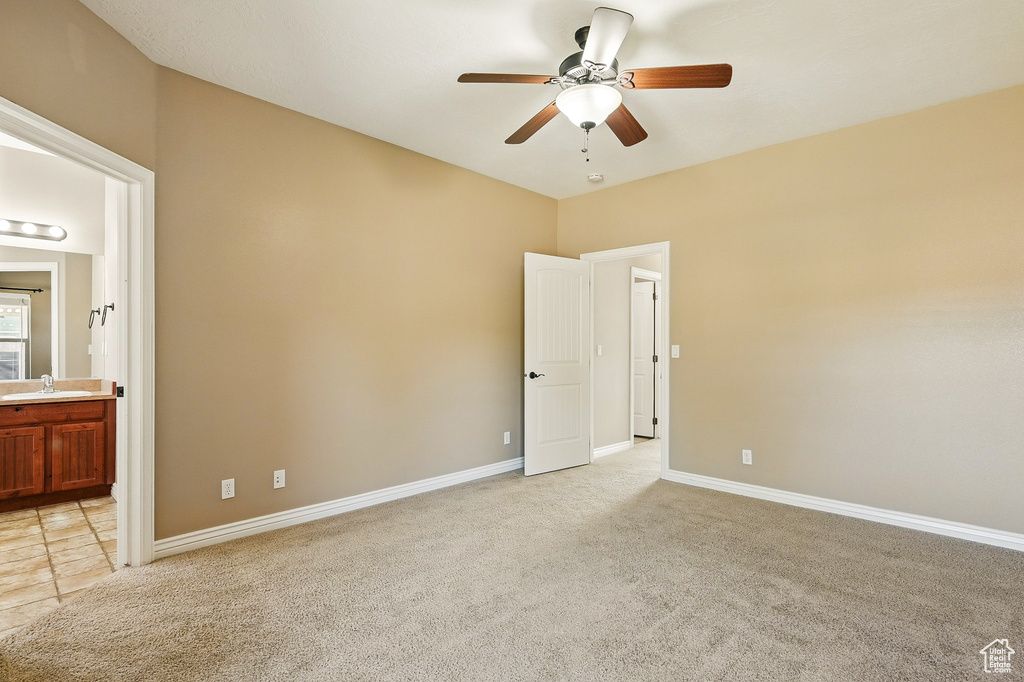 Unfurnished bedroom featuring baseboards, light colored carpet, and a sink
