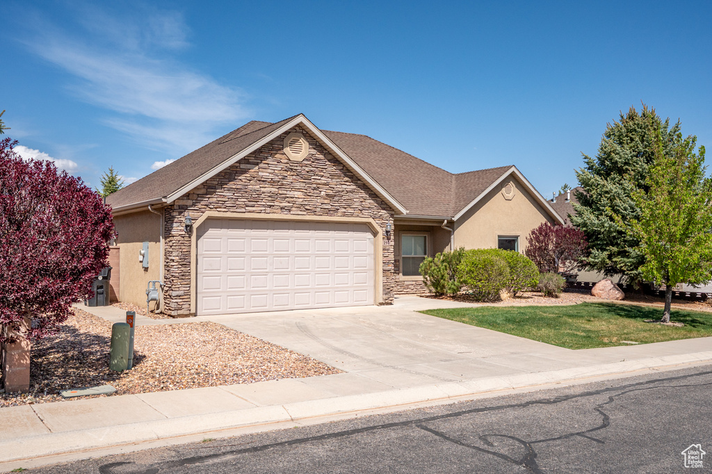 Single story home with concrete driveway, a garage, stone siding, and stucco siding