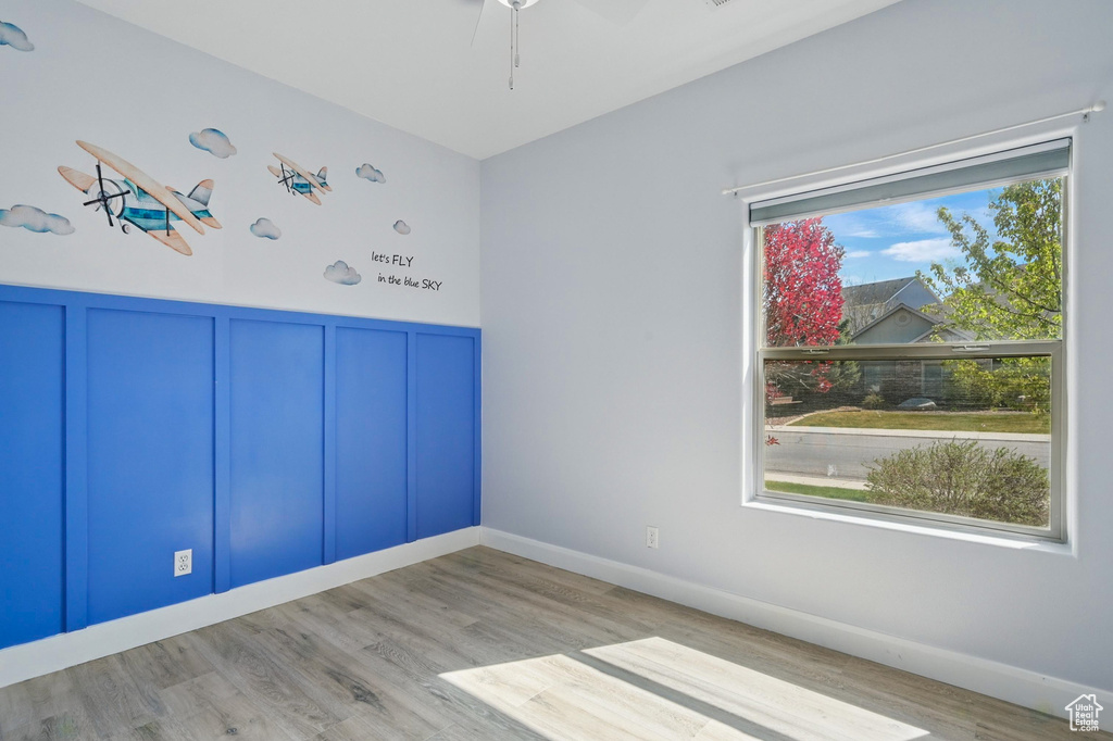 Spare room featuring wainscoting, ceiling fan, a decorative wall, and wood finished floors
