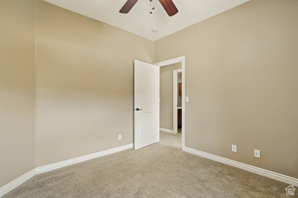 Empty room with baseboards, ceiling fan, and light carpet