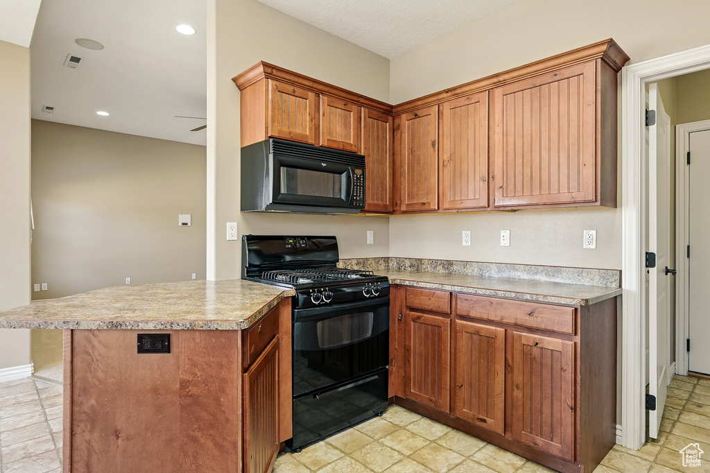 Kitchen featuring light countertops, a peninsula, brown cabinetry, and black appliances