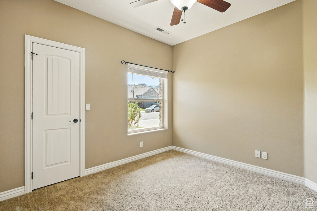 Carpeted spare room with a ceiling fan, baseboards, and visible vents