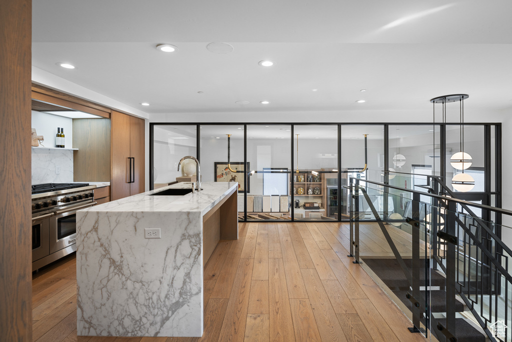 Kitchen featuring range with two ovens, modern cabinets, light wood-type flooring, and a sink