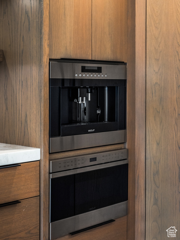 Details with stainless steel oven, brown cabinetry, oven, and modern cabinets