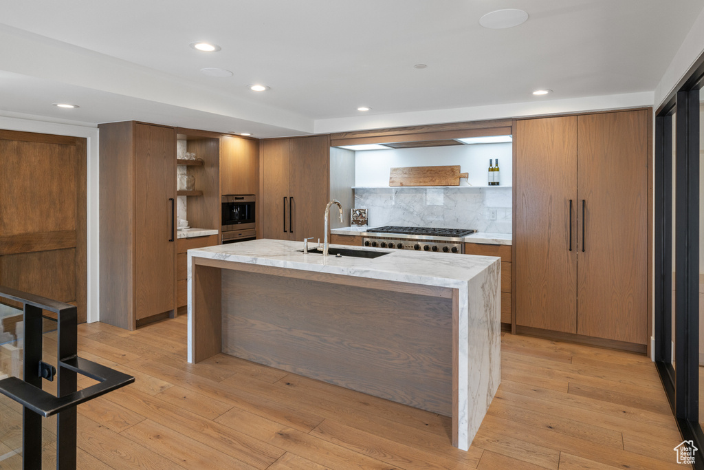Kitchen featuring a sink, decorative backsplash, brown cabinets, open shelves, and appliances with stainless steel finishes