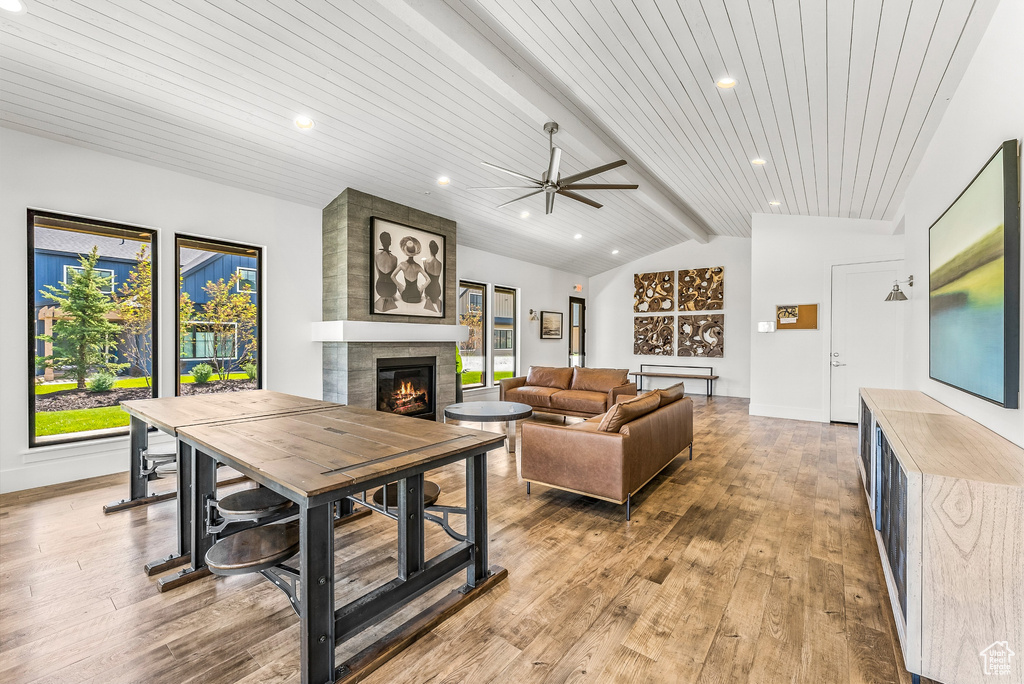 Living room featuring wood ceiling, a ceiling fan, a tile fireplace, lofted ceiling with beams, and light wood finished floors