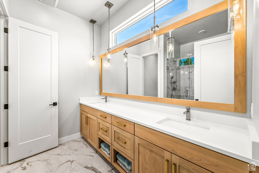 Bathroom featuring double vanity, a sink, marble finish floor, and a stall shower