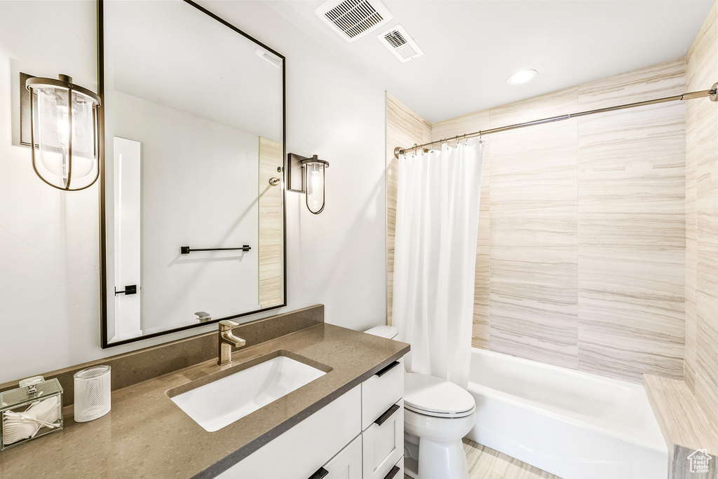 Bathroom with vanity, shower / bath combo with shower curtain, toilet, and visible vents