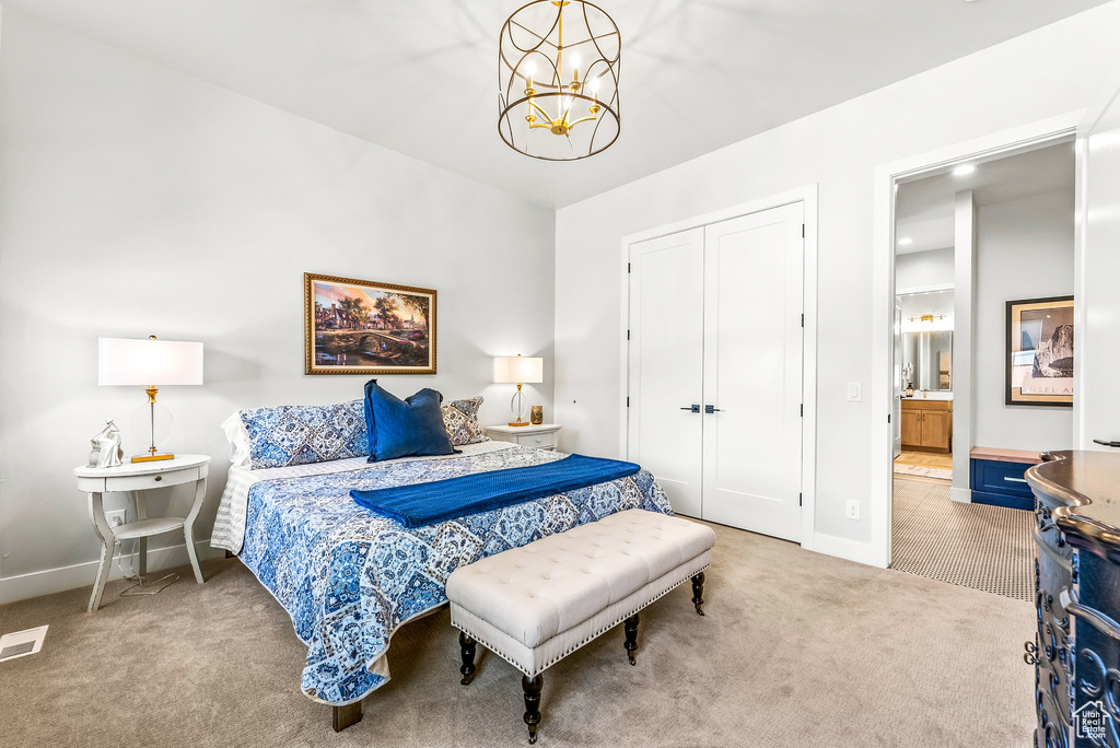 Carpeted bedroom with a notable chandelier, baseboards, ensuite bathroom, visible vents, and a closet