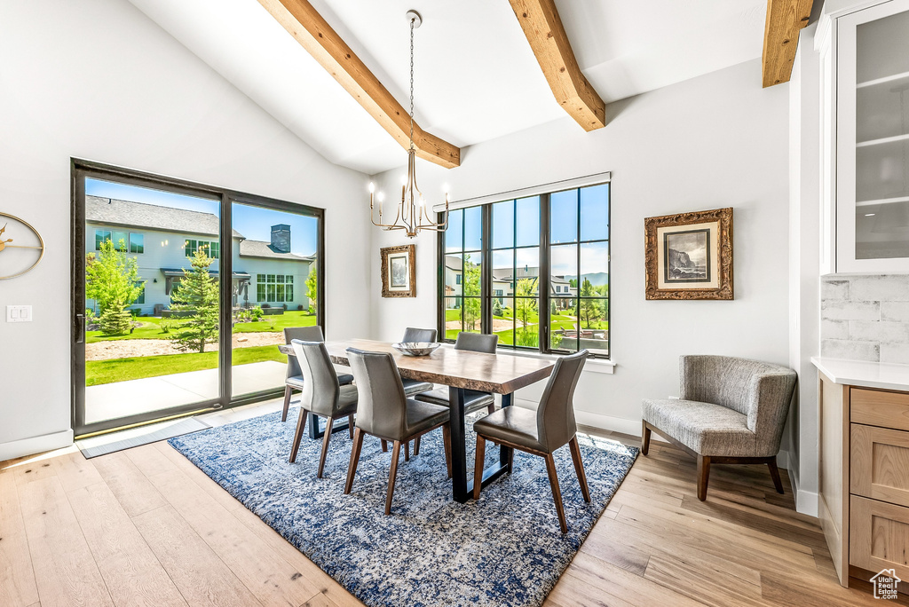 Dining space with light wood-type flooring, baseboards, a chandelier, and beamed ceiling
