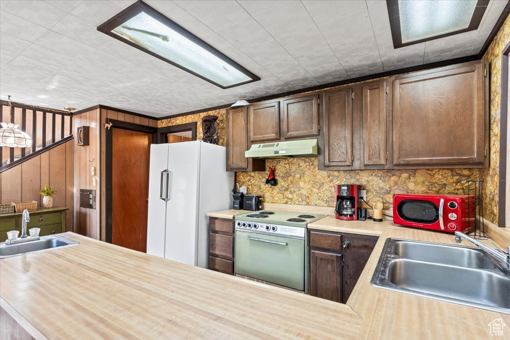 Kitchen featuring a sink, freestanding refrigerator, range with electric stovetop, and under cabinet range hood