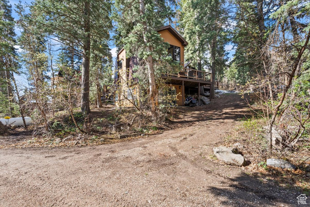 View of side of home featuring a deck and dirt driveway