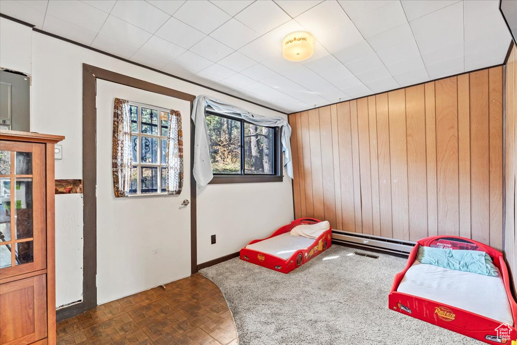 Bedroom with wood walls and a baseboard radiator