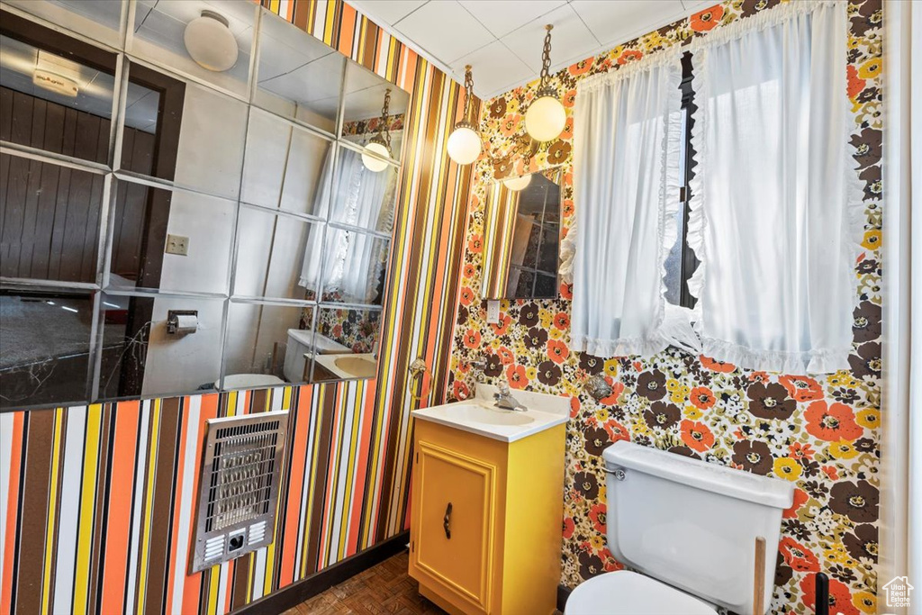 Bathroom featuring vanity, heating unit, toilet, and wallpapered walls