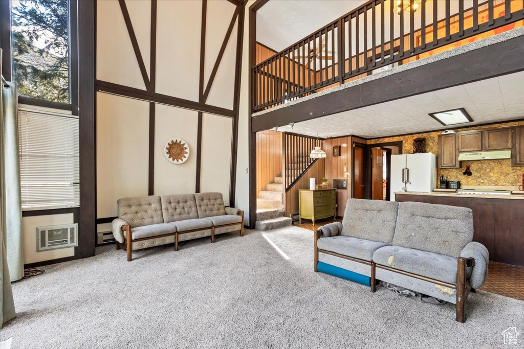 Carpeted living area with stairs and a high ceiling