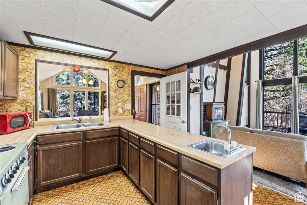 Kitchen featuring a sink, light countertops, wallpapered walls, and electric range