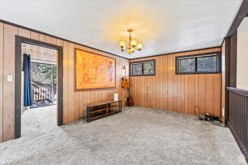 Carpeted empty room with an inviting chandelier and wood walls