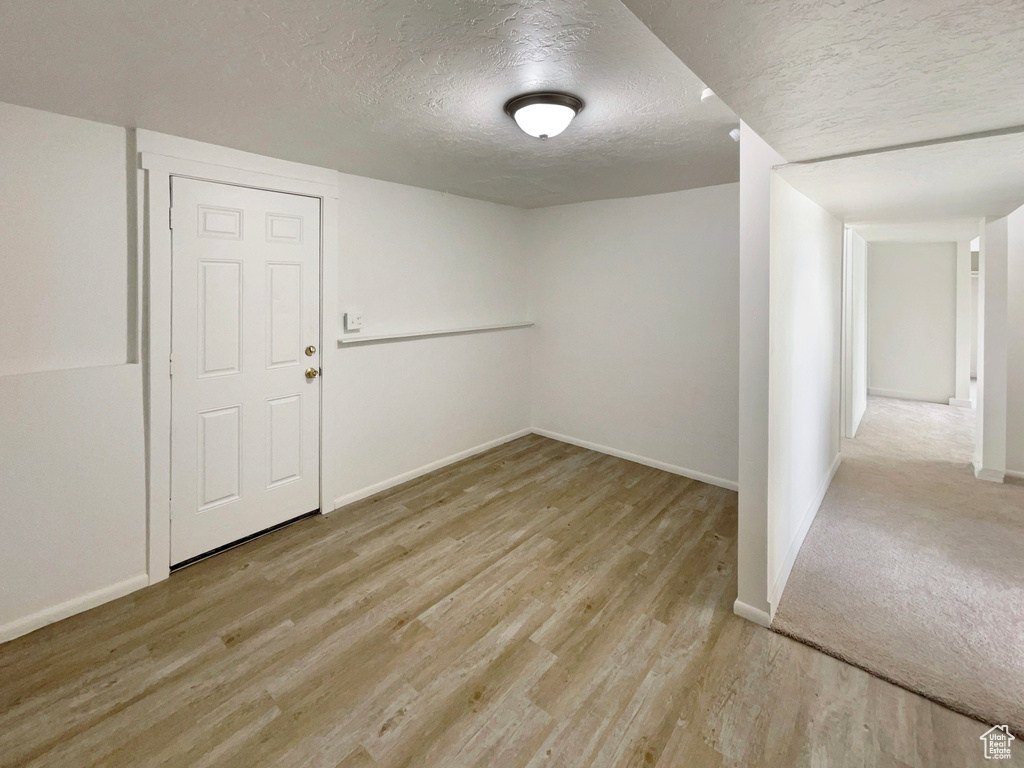 Spare room featuring baseboards, a textured ceiling, and wood finished floors