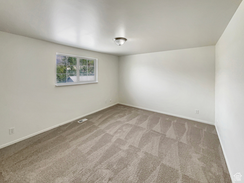Carpeted spare room featuring baseboards and visible vents
