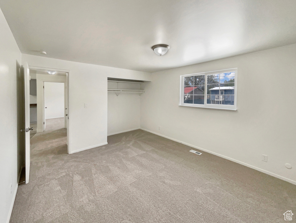 Unfurnished bedroom with baseboards, carpet, a closet, and visible vents