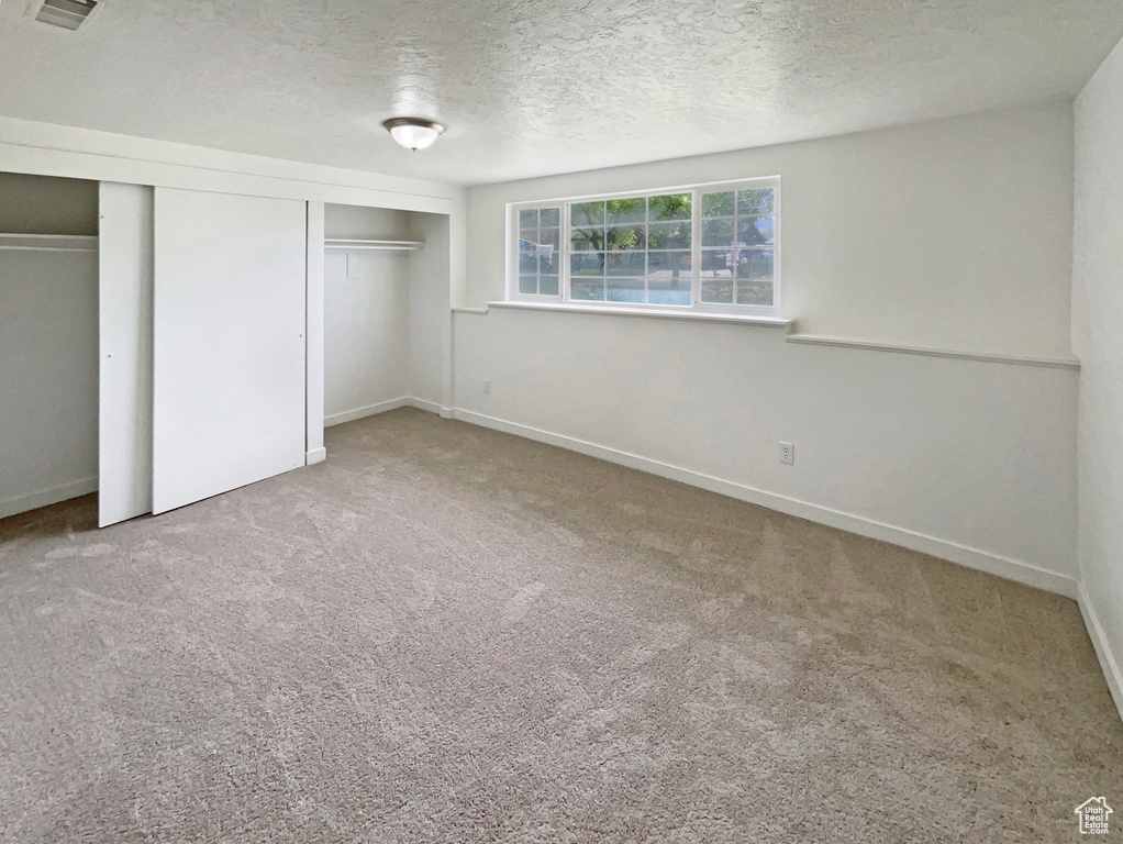 Unfurnished bedroom featuring carpet floors, a textured ceiling, baseboards, and visible vents