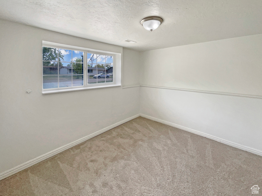 Carpeted empty room featuring baseboards and a textured ceiling