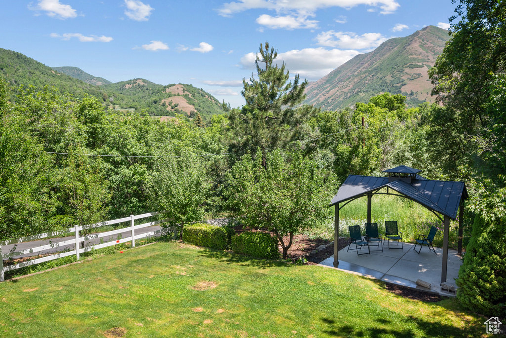 View of yard with a mountain view, a gazebo, a patio area, and a wooded view