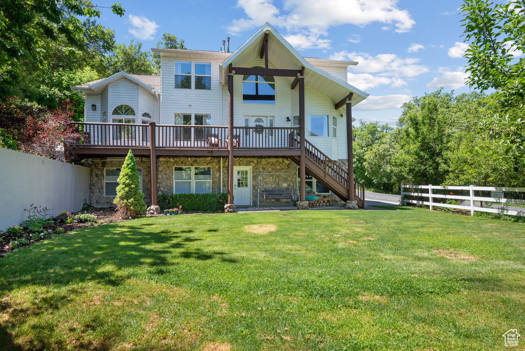 Rear view of house featuring a deck, stone siding, and stairway