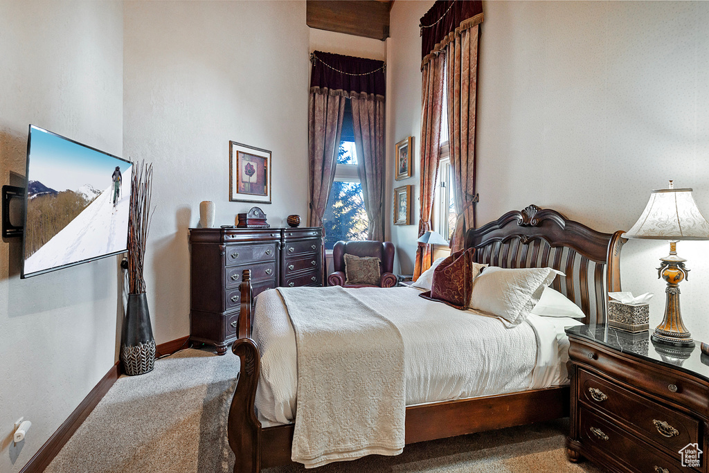Carpeted bedroom featuring baseboards and a high ceiling