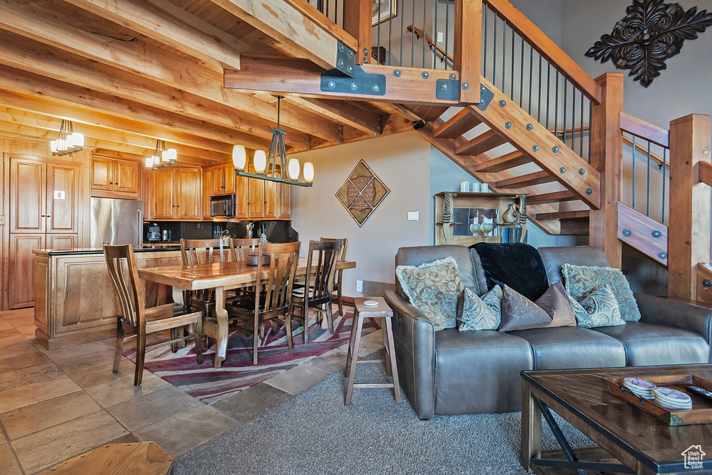 Living room with stairway, a notable chandelier, and beam ceiling