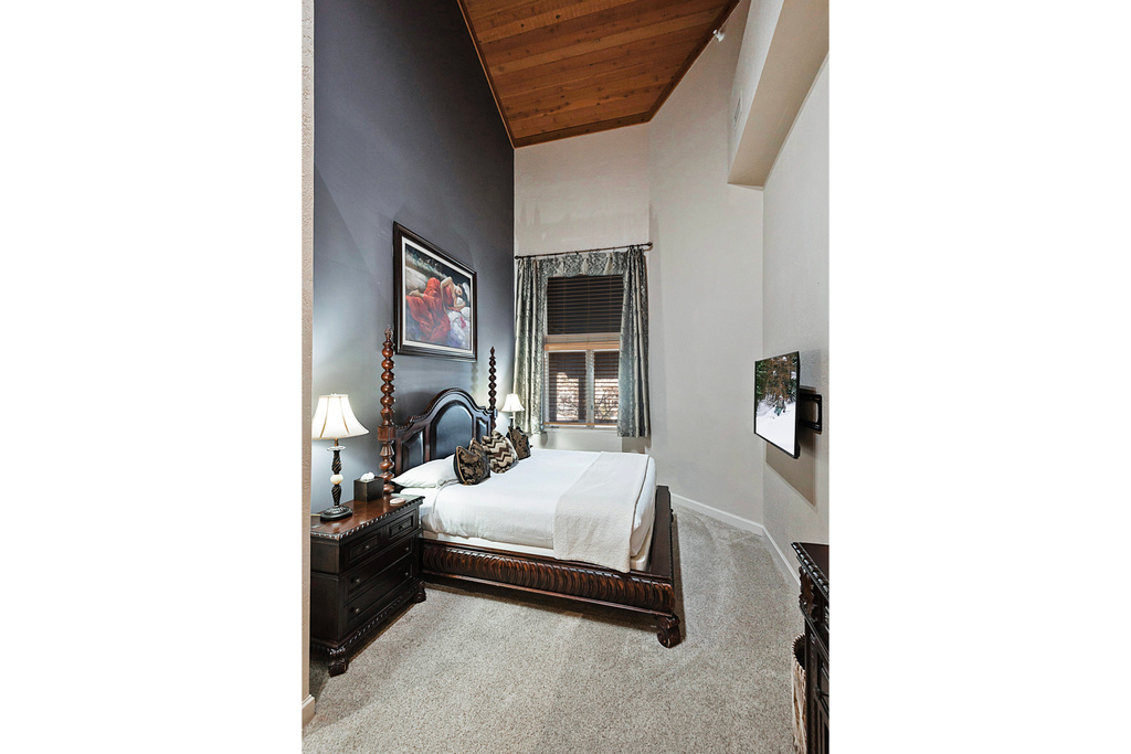 Bedroom featuring light carpet, baseboards, a high ceiling, and wood ceiling