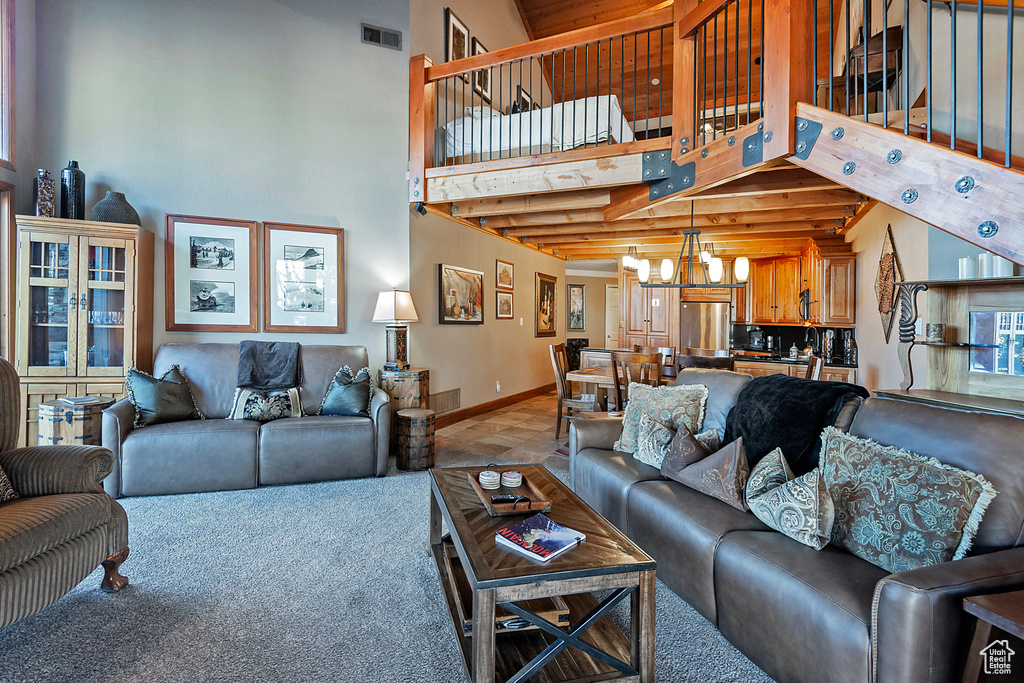 Living room featuring an inviting chandelier, carpet, baseboards, a towering ceiling, and visible vents