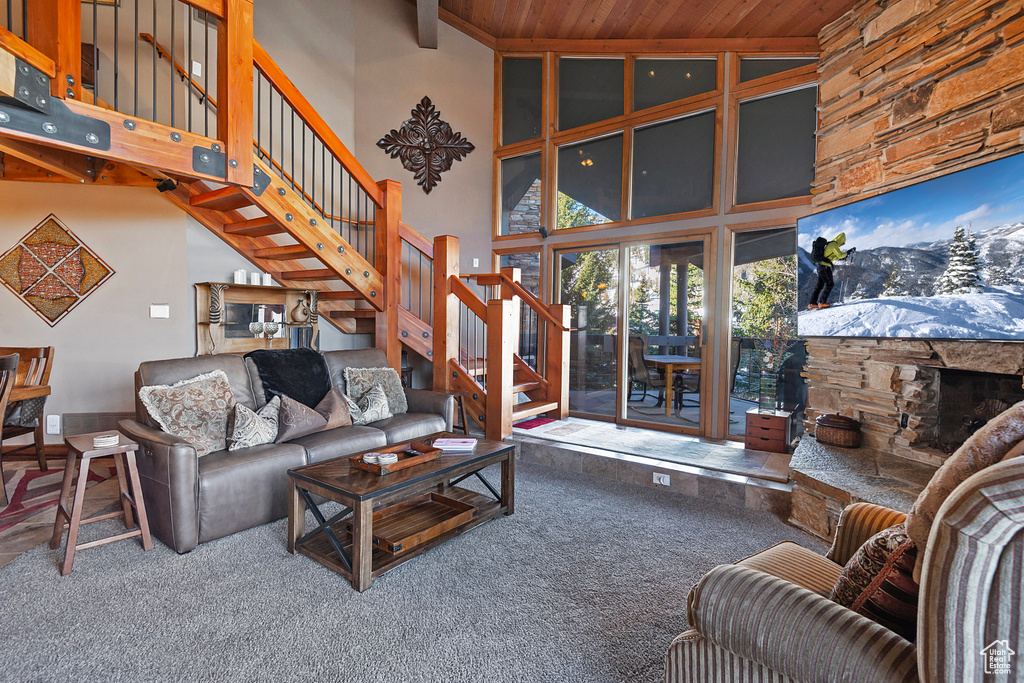Carpeted living room with stairs, a fireplace, high vaulted ceiling, and wood ceiling