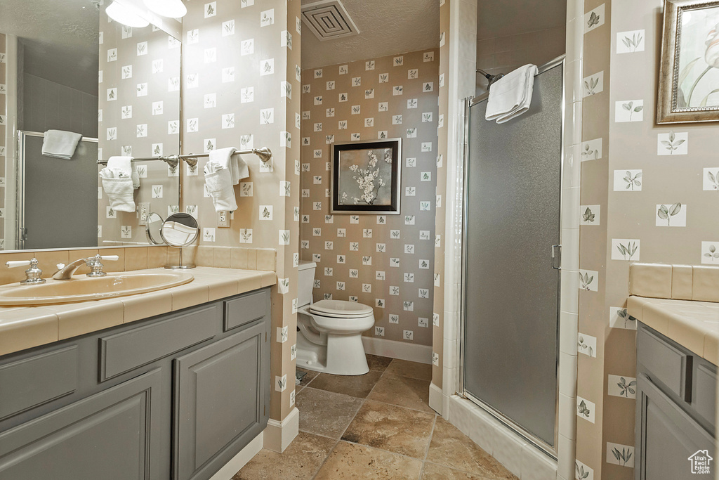 Full bath featuring a stall shower, toilet, vanity, baseboards, and wallpapered walls