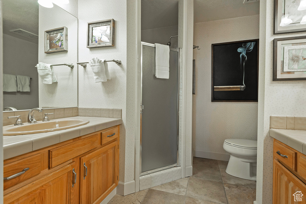 Bathroom featuring visible vents, a shower stall, baseboards, toilet, and vanity