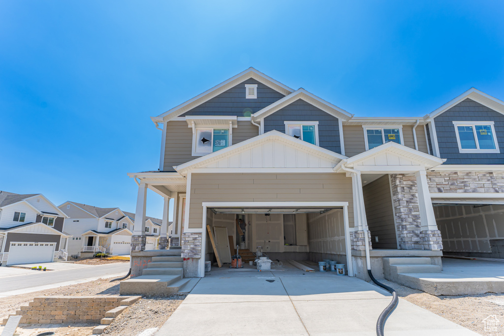 View of front of home featuring concrete driveway, stone siding, board and batten siding, and an attached garage