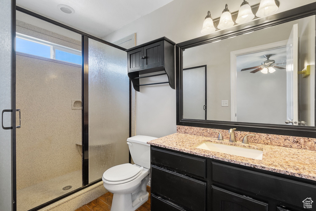 Full bath with toilet, a ceiling fan, vanity, and a stall shower