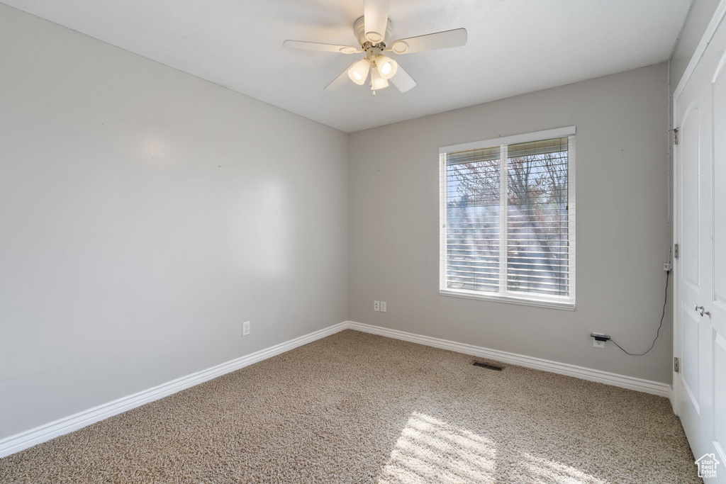 Empty room featuring ceiling fan, carpet floors, visible vents, and baseboards