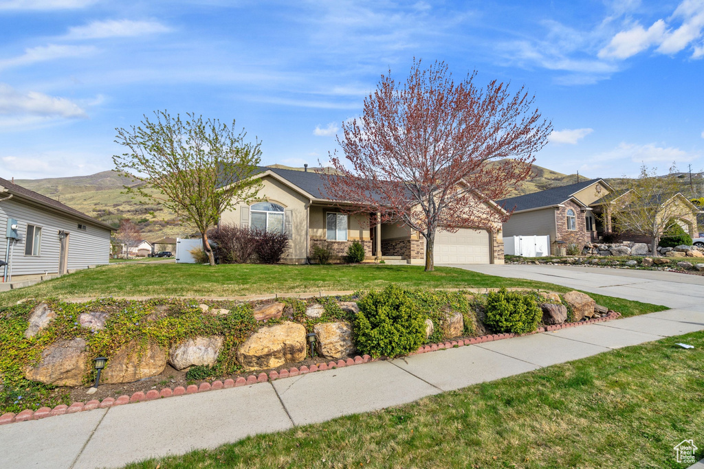 Ranch-style home featuring an attached garage, a front yard, a mountain view, and concrete driveway