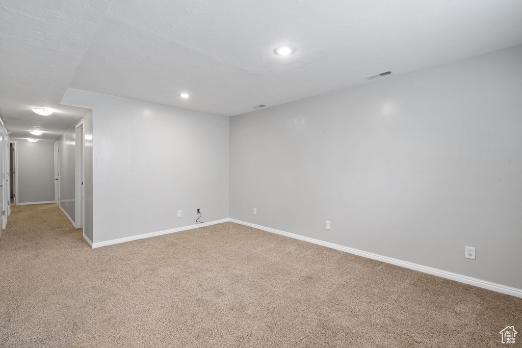 Finished below grade area featuring light colored carpet, baseboards, visible vents, and recessed lighting
