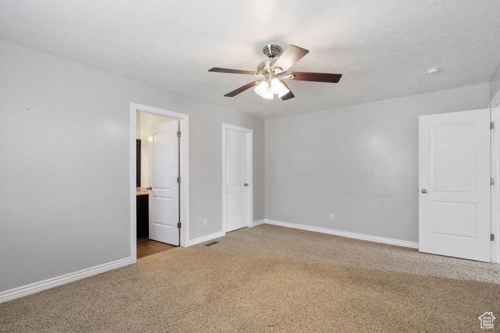 Unfurnished bedroom with carpet floors, a ceiling fan, ensuite bathroom, and baseboards