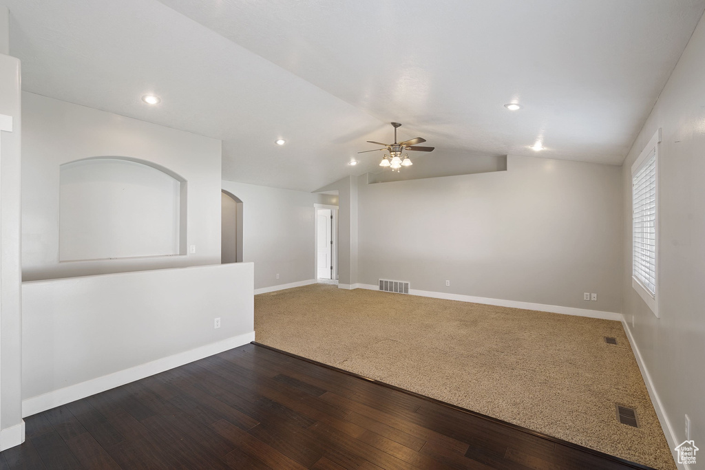 Carpeted empty room with baseboards, a ceiling fan, visible vents, and lofted ceiling