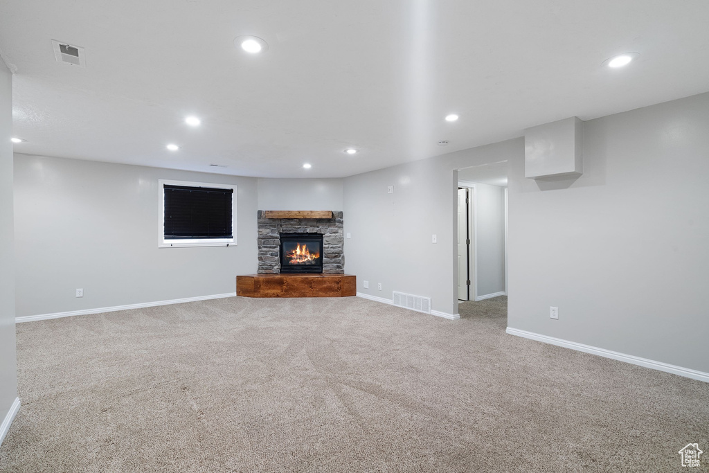 Unfurnished living room with a fireplace, carpet flooring, visible vents, and recessed lighting