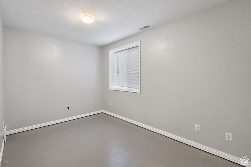 Spare room with baseboards, visible vents, and finished concrete flooring