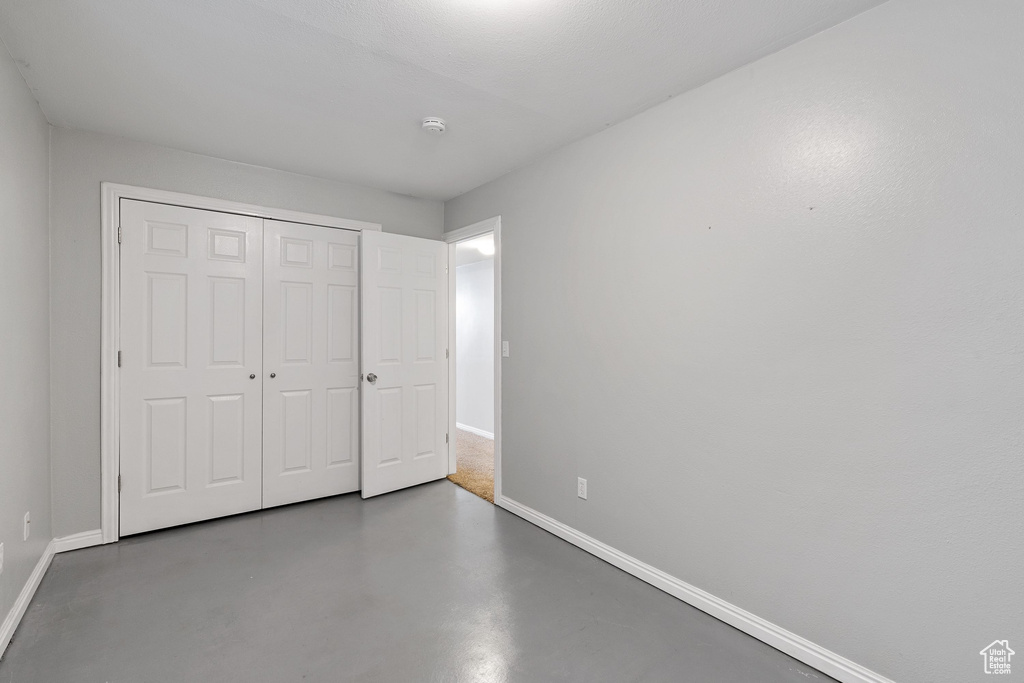 Unfurnished bedroom featuring baseboards, concrete floors, and a closet