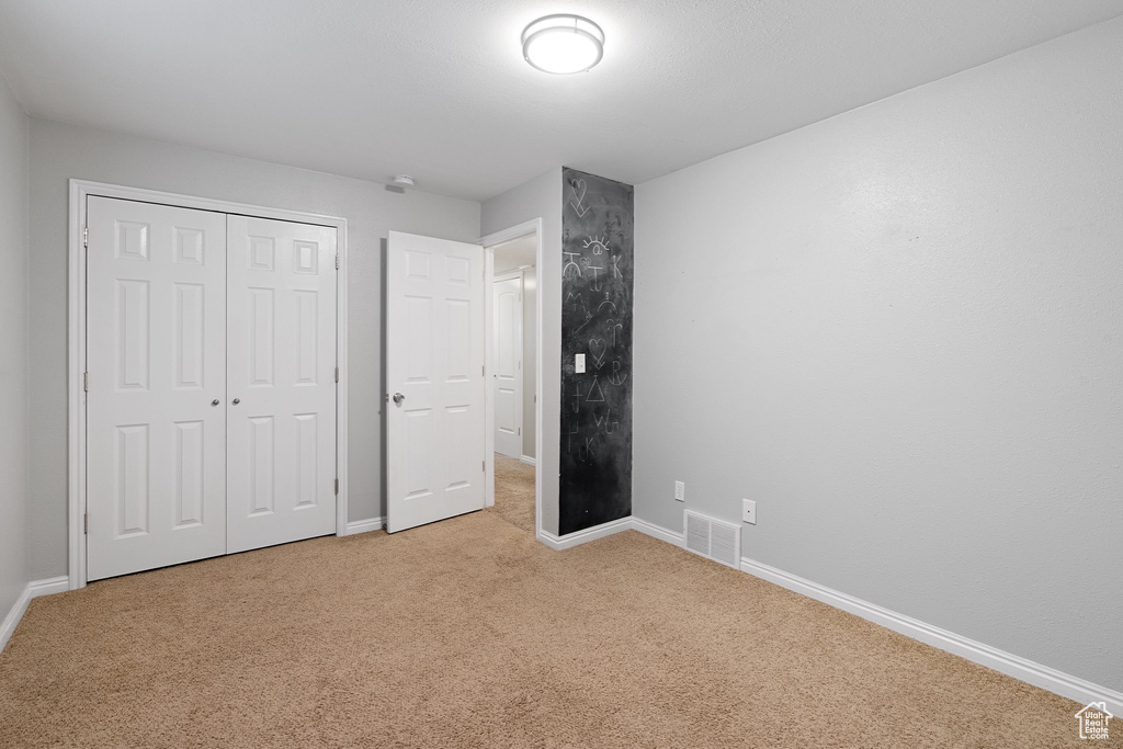 Unfurnished bedroom featuring light carpet, visible vents, and baseboards