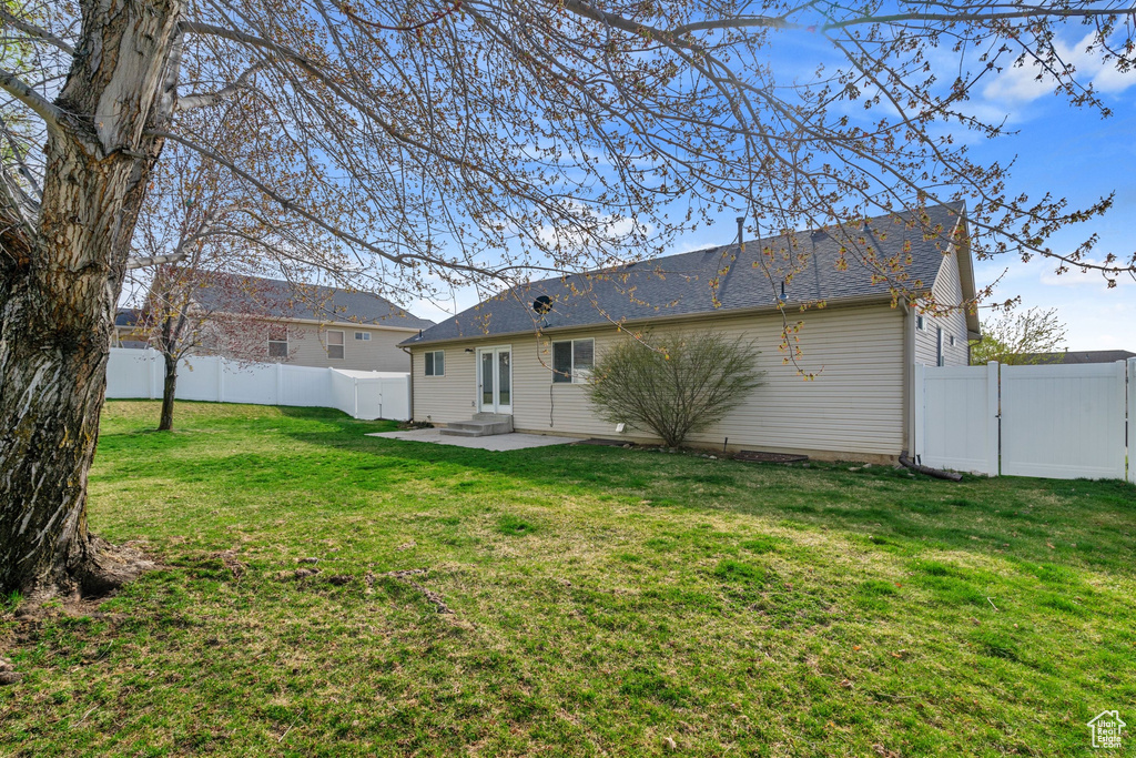 Back of house featuring a fenced backyard, a gate, entry steps, a yard, and a patio