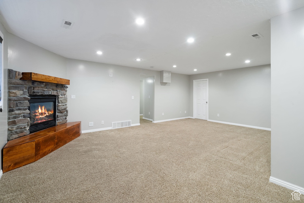 Unfurnished living room featuring a stone fireplace, visible vents, carpet floors, and recessed lighting